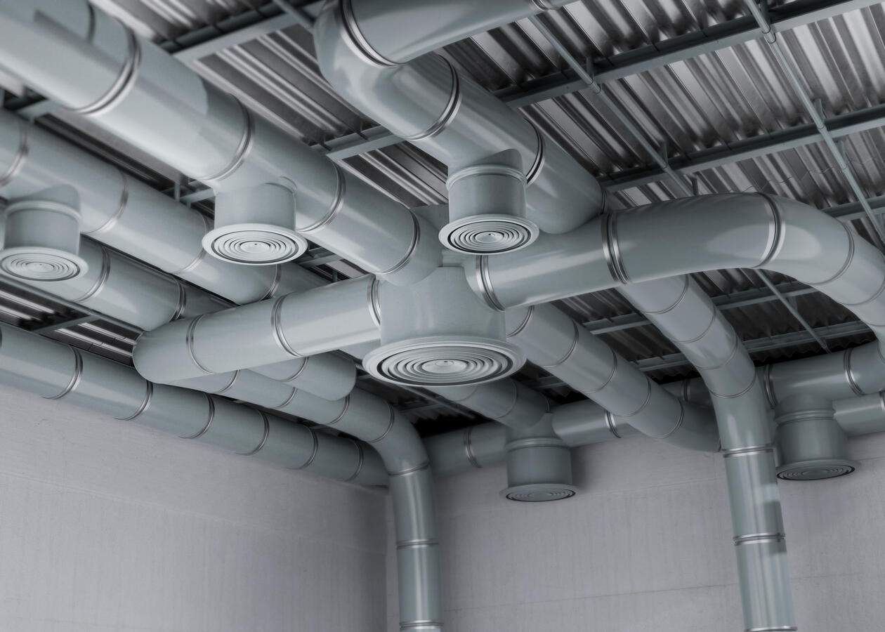 HVAC Ductwork Round ventilation ducts and ceiling diffusers beneath a metal roof.
