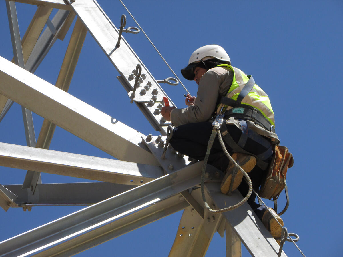 Transmission Towers Technician wearing a safety harness working on a steel transmission tower.